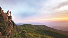 Two hikers on a cliff overlooking the mountain views in Shenandoah National Park in Virginia USA