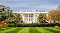The White House in Washington, DC, USA, in front of a manicured, green lawn on a sunny day.