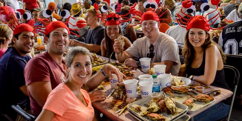 Annapolis Crab Feast_CREDIT Visit Annapolis (2).jpeg A group of people wearing crab hats enjoying the feast