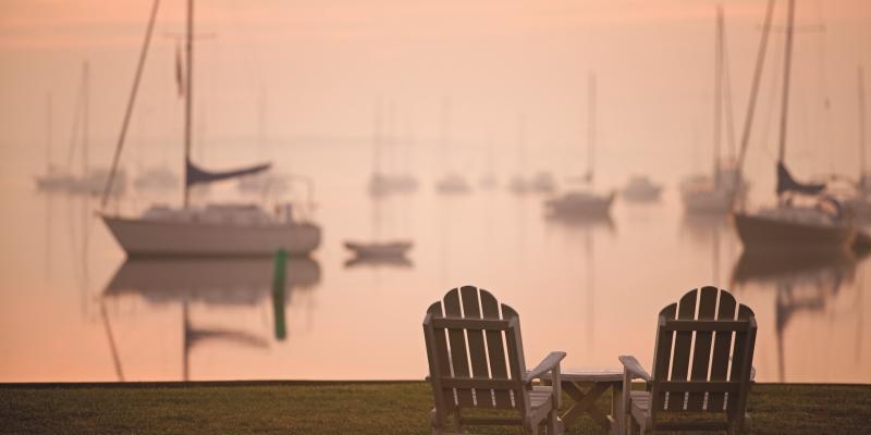 Two chairs at sunset in front of the marina at Inn at Perry Cabin St Michaels Harbor in Maryland, USA