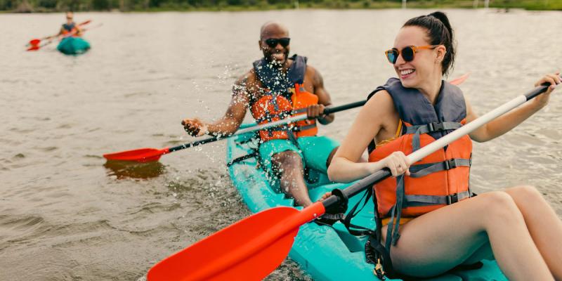 Two people kayaking in a green kayak on calm waters in Virginia Beach, Virginia, USA