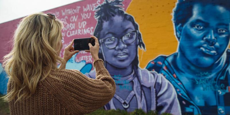 A person takes a picture of a mural with her cellphone in the ViBe Creative District of Virginia Beach, Virginia, USA.