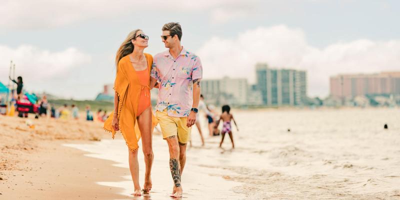 Two people hold hands and walk at low tide at Virginia Beach, Virginia, USA