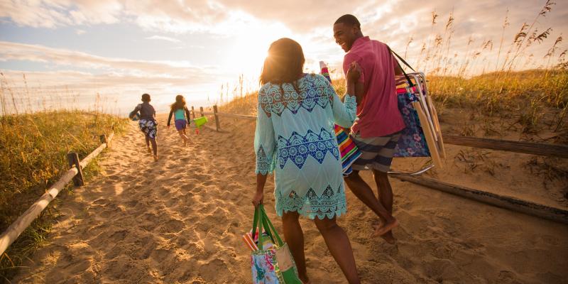 A family walking up a dune towards the sunset