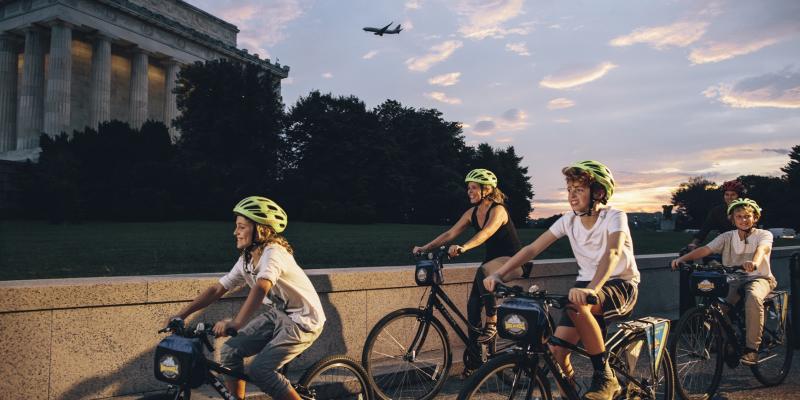 A family cycles past the Lincoln Memorial at dusk