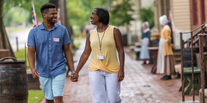 A couple holds hands as they stroll down the bricked streets of Williamsburg, Virginia, USA