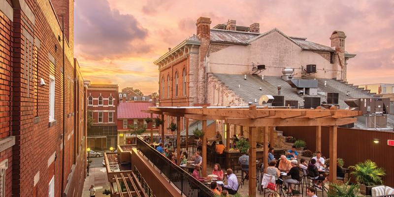 People dining during pink-tinted dusk on a rooftop in Brewer's Alley in Frederick, Maryland, USA