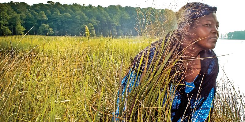 An actress portraying Harriet Tubman crouches among a field along the Harriet Tubman Underground Railroad Byway in Maryland, USA.