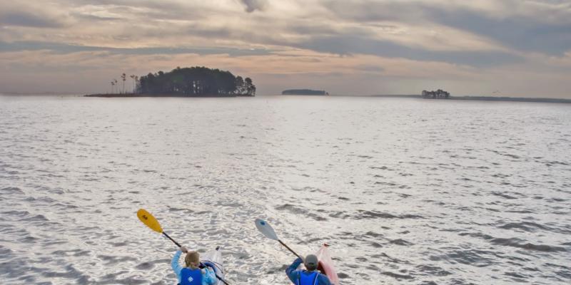 Two people kayak at sunset at Blackwater National Wildlife Refuge in Cambridge, Maryland, USA