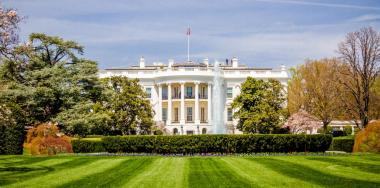 The White House in Washington, DC, USA, in front of a manicured, green lawn on a sunny day.