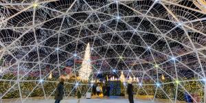 Visitors gaze upwards in a domed installation.