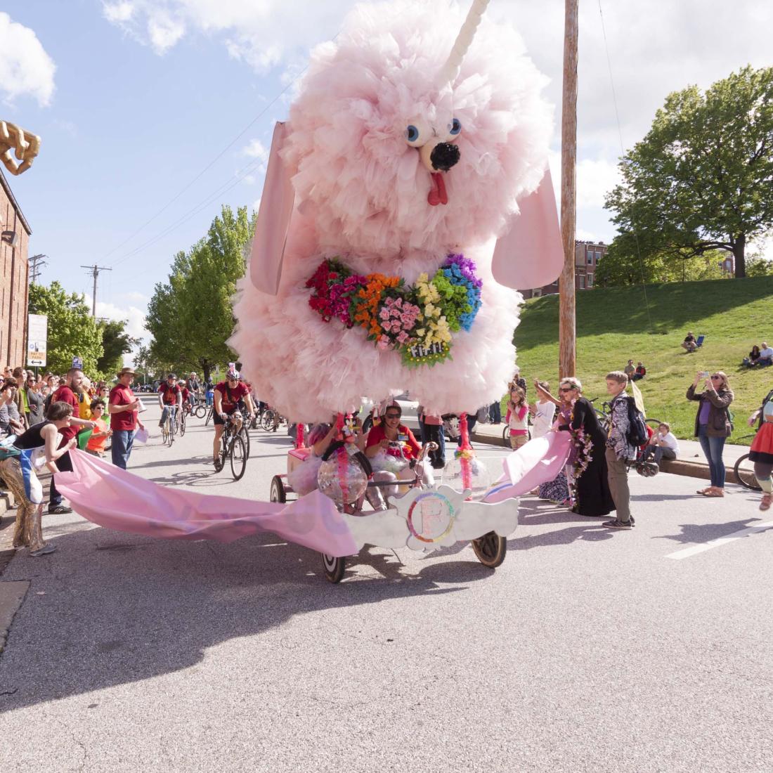 A kinetic poodle sculpture passes spectators