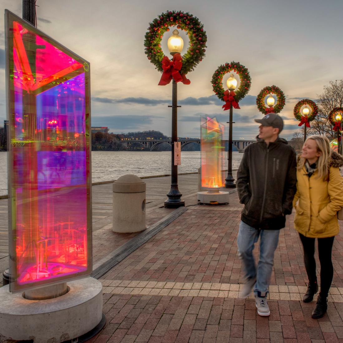 A couple walks along the Potomac River waterfront decorated for the holidays