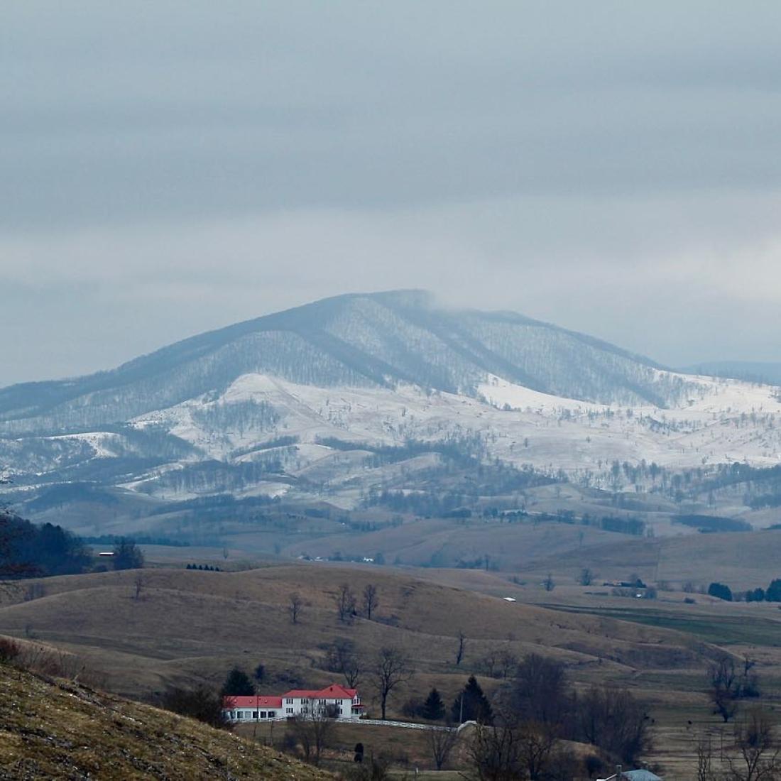 A scenic view of rolling hills and snowy mountains