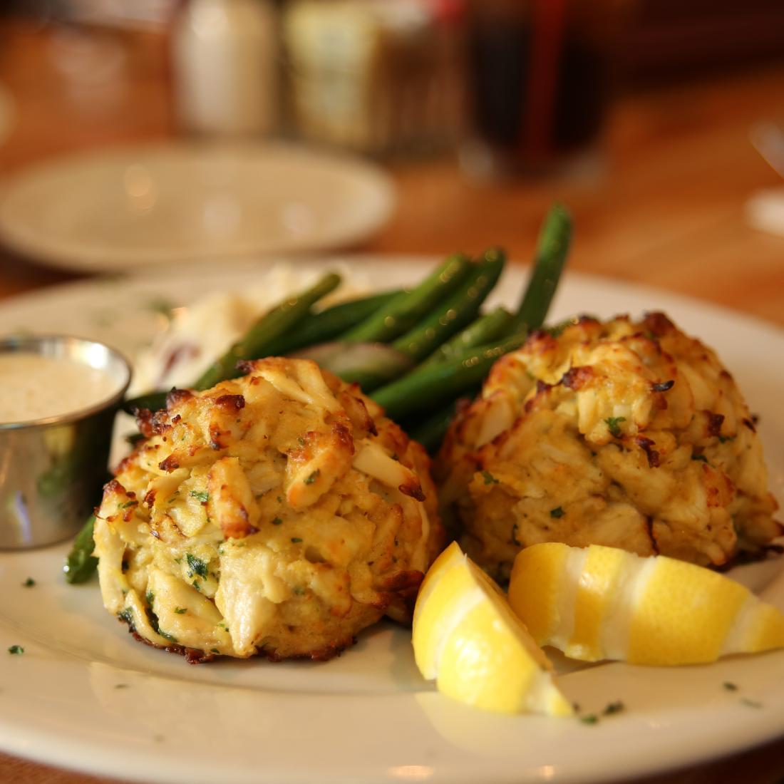 A dish of crab cakes with green beans