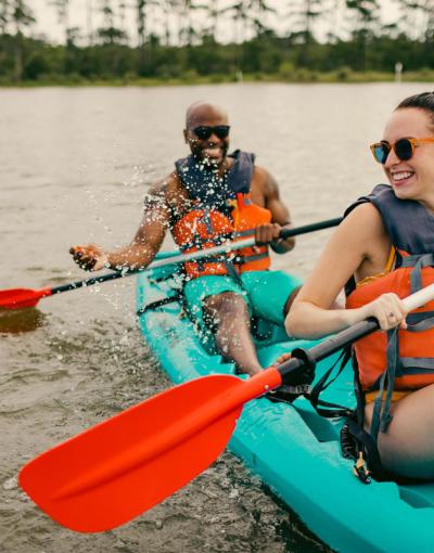 Two people kayaking in a green kayak on calm waters in Virginia Beach, Virginia, USA