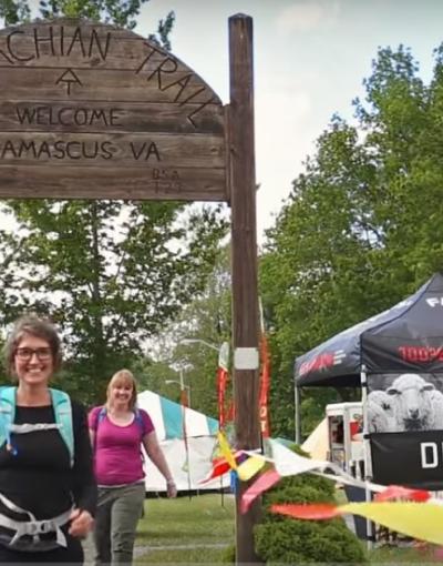 Hikers walking below an Appalachian trail sign