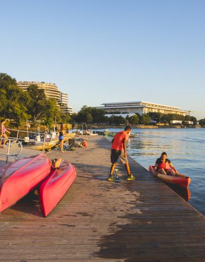 A person helps a kayaker into a red kayak on the waterfront of the Georgetown neighbourhood in Washington, DC