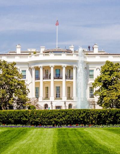 The White House in Washington, DC, USA, in front of a manicured, green lawn on a sunny day.